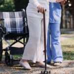Senior getting off the wheelchair with help of cane