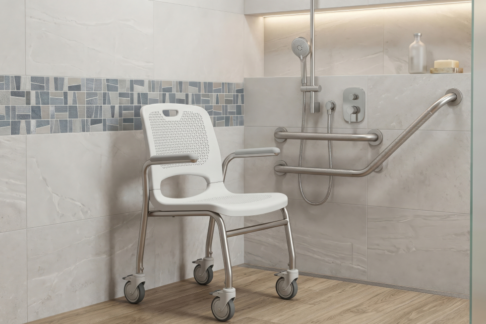 Well-maintained mobile bath chair with armrests and wheels inside a tiled accessible bathroom with safety grab bars.