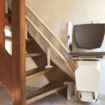 Residential custom stairlift chair mounted on an open-riser wooden staircase for safe multi-floor accessibility