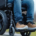 A specialized tilt-in-space manual wheelchair with treaded tires and adjustable footrests for ergonomic outdoor mobility.