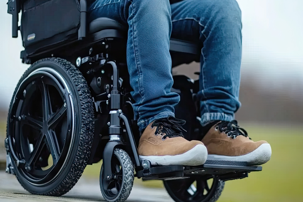 A specialized tilt-in-space manual wheelchair with treaded tires and adjustable footrests for ergonomic outdoor mobility.